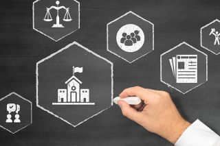 Foto: Person malt Zeichen auf Tafel mit Kreide